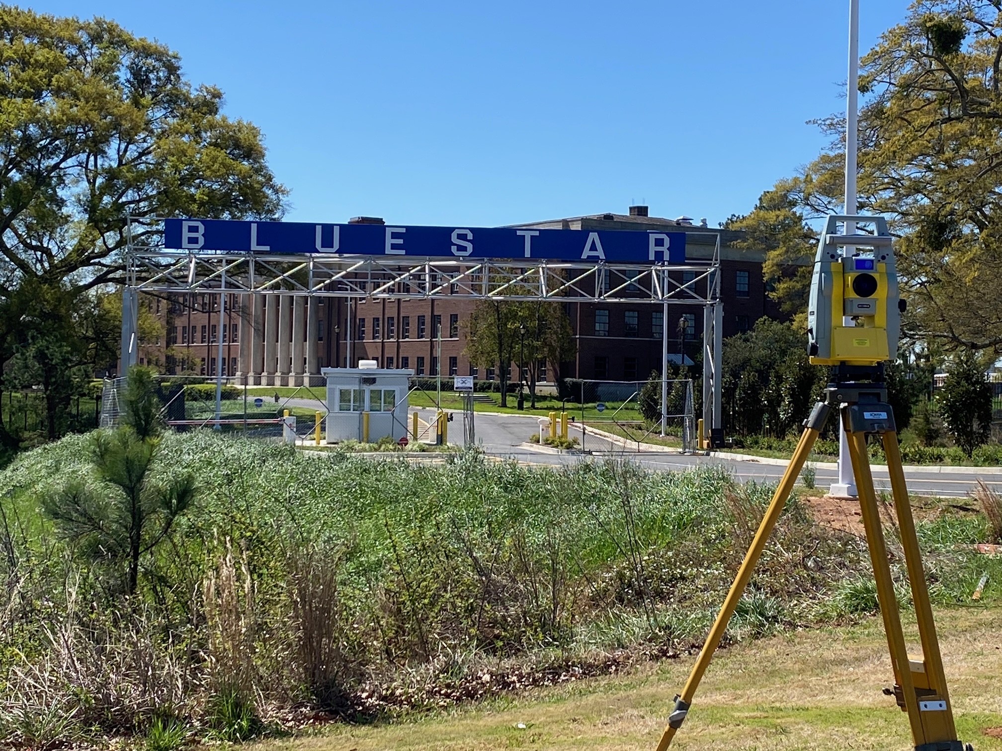 A survey mapping camera on a tripod sitting on the lawn in front of the Blue Star Studios facility gates.